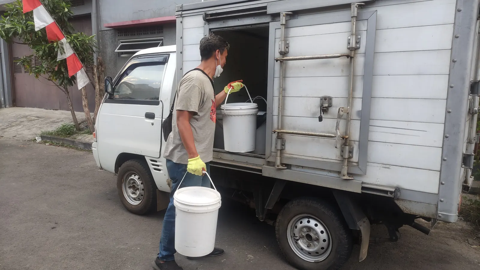 Petugas Ngadaur memuat ember sampah organik ke mobil bak terbuka