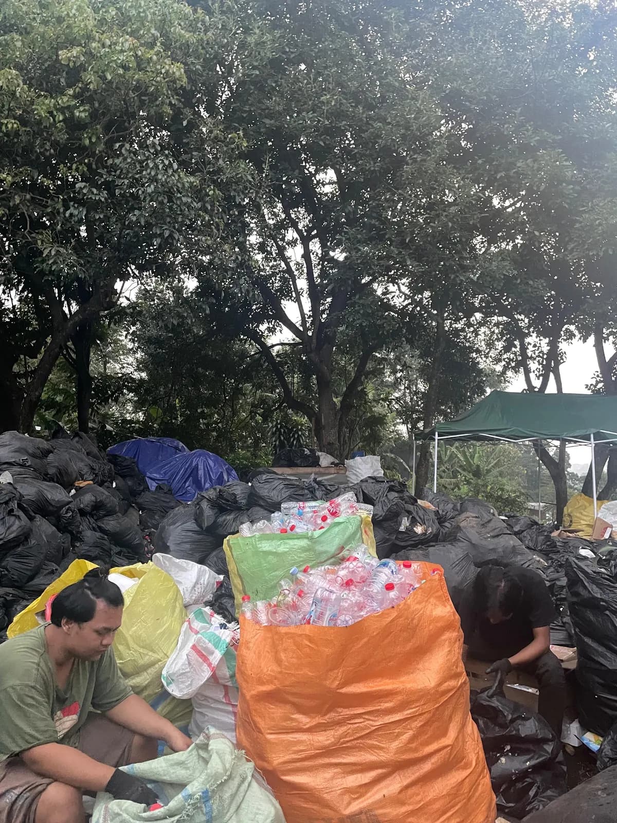 Petugas memilah sampah anorganik ke karung di area pemilahan Ngadaur